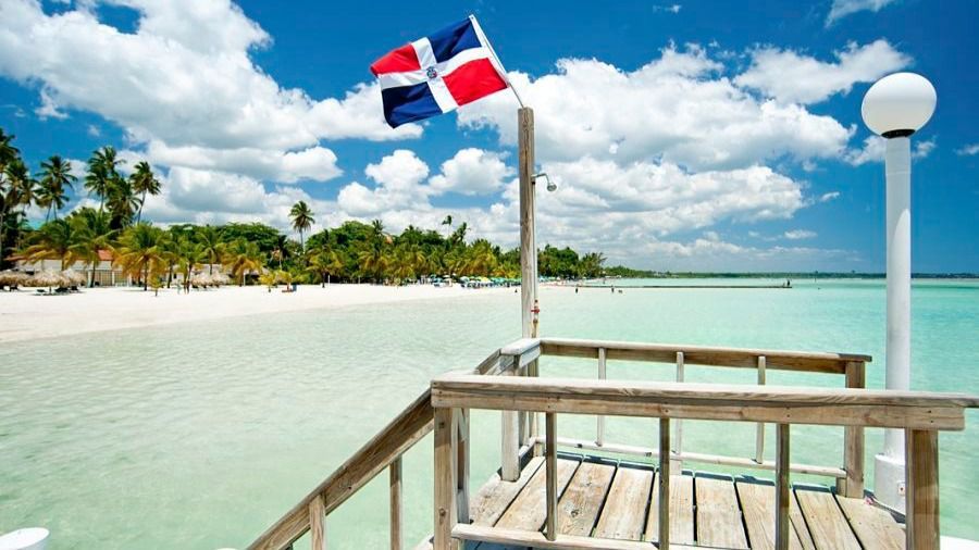 Playa caribeña con bandera dominicana y muelle