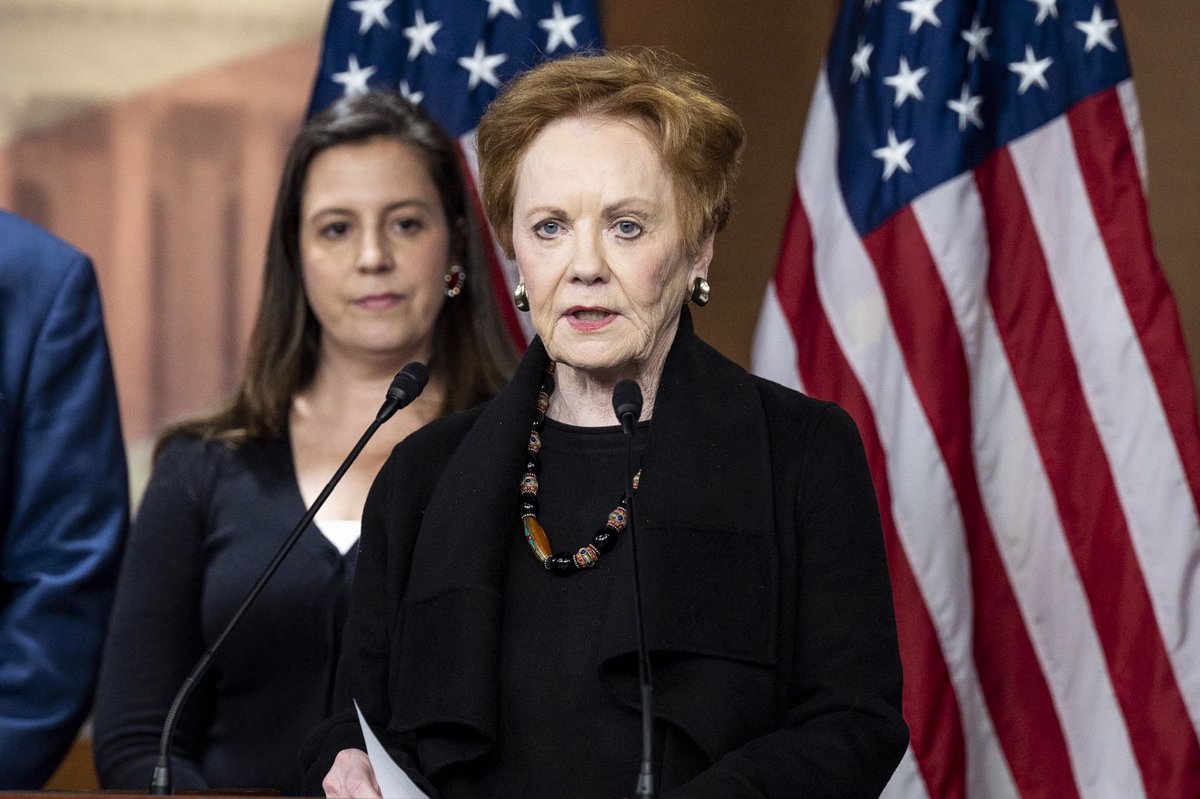 Mujer mayor hablando en micrófono, banderas de EE.UU.