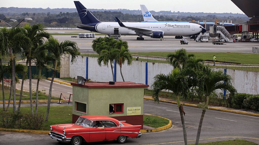 Aeropuerto con aviones, coche clásico rojo y palmeras