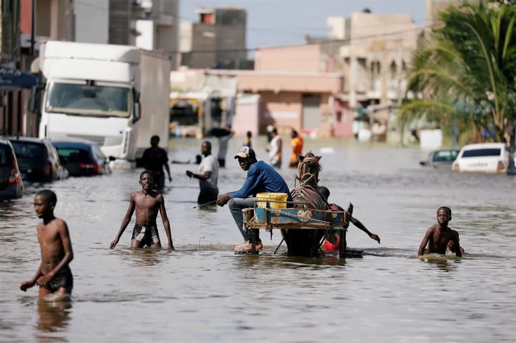 Personas navegando calle inundada con carro