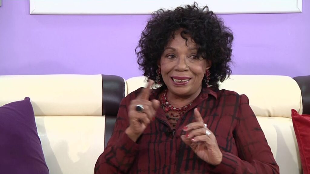 Mujer sonriente hablando y gesticulando en un sofá