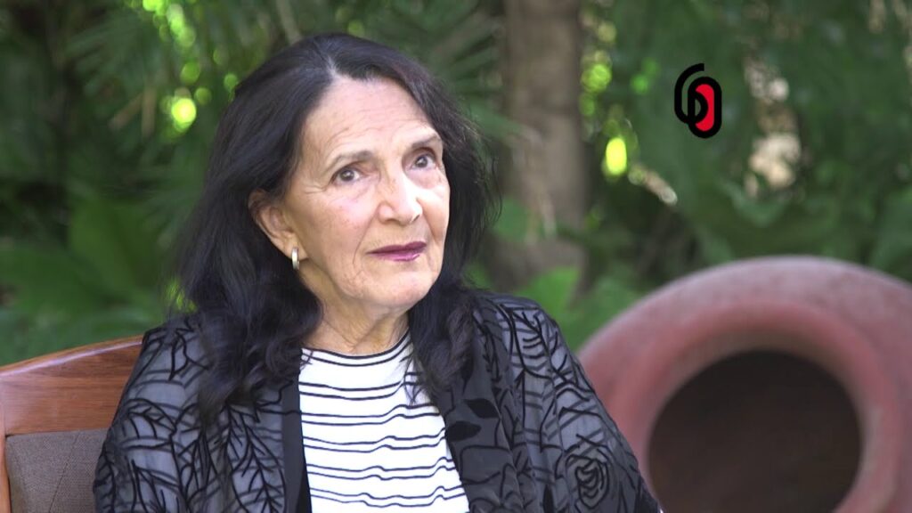 Mujer mayor sentada al aire libre mirando a cámara