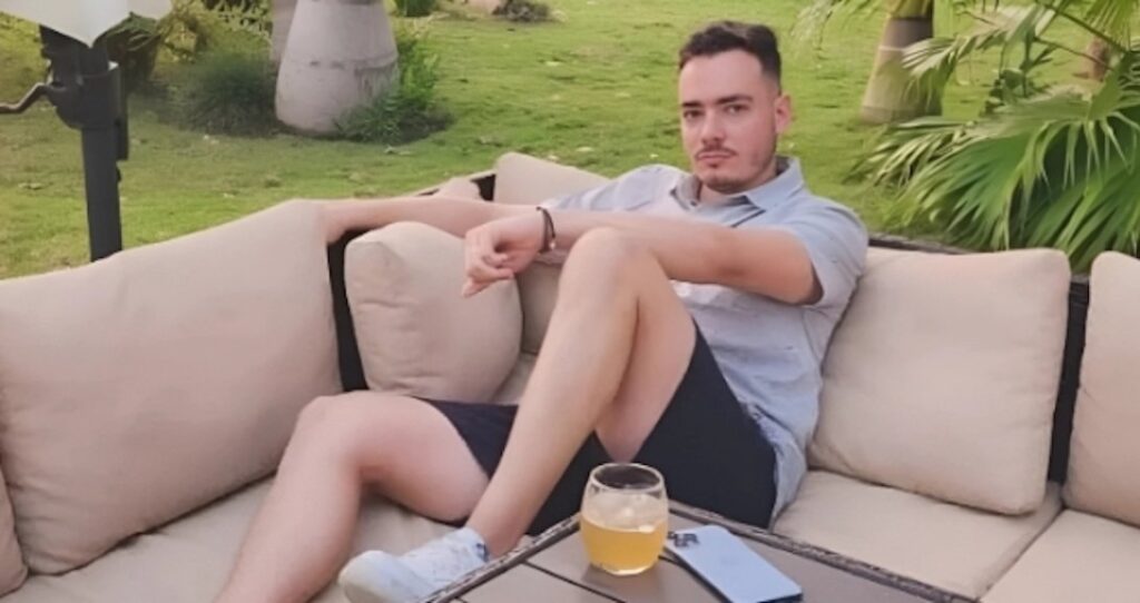 Hombre relajado con bebida en sofá exterior