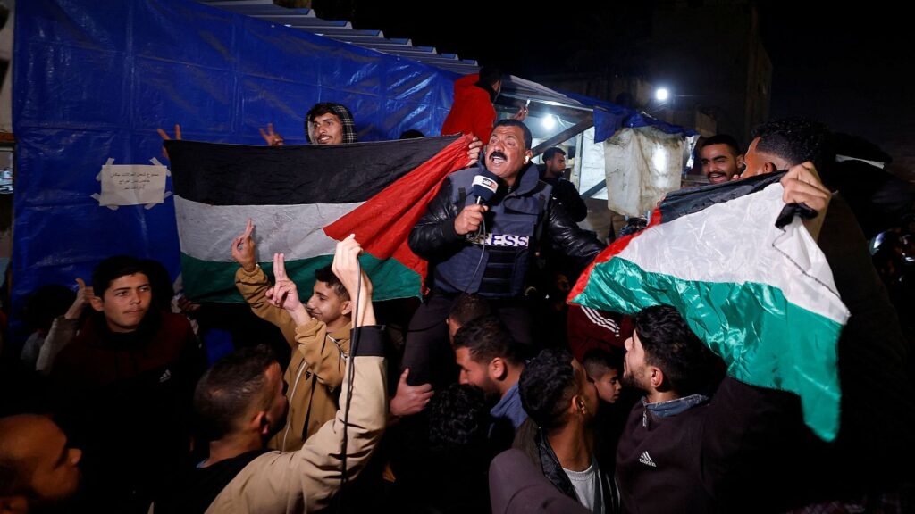 Periodista informando en manifestación con banderas