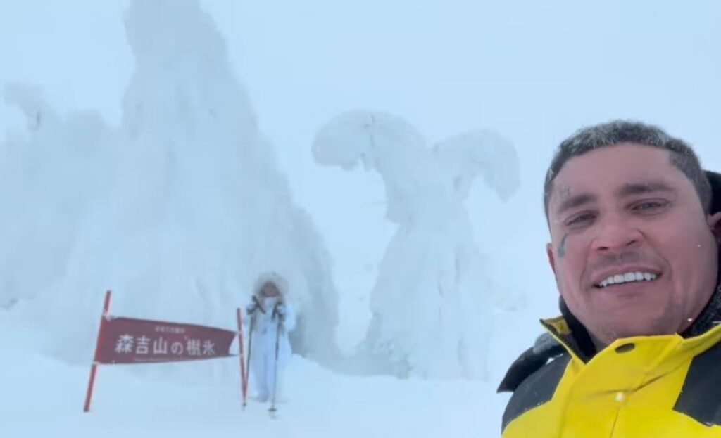 Hombre sonriente con figura de nieve al fondo