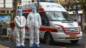 Sanitarios en trajes de protección junto a ambulancia