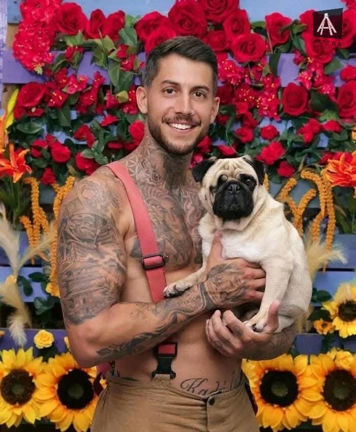 Hombre tatuado sostiene carlino frente a flores