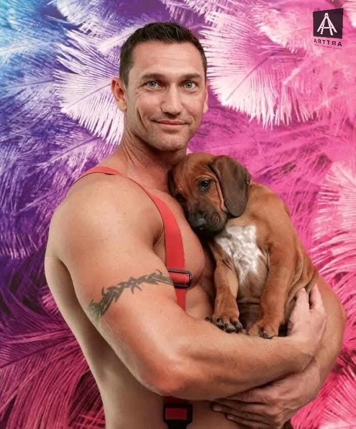 Hombre sonriente sostiene cachorro contra fondo colorido