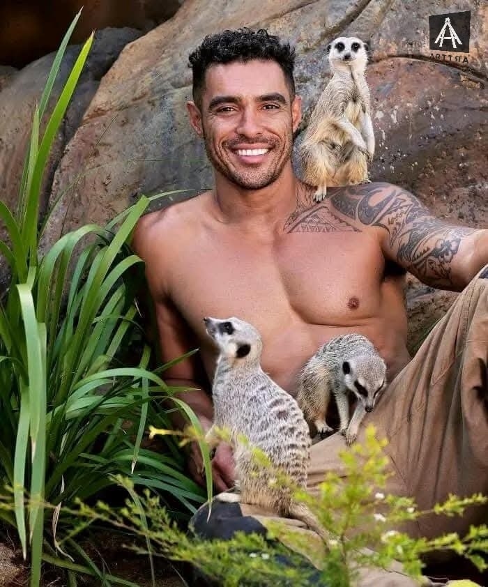 Hombre sonriente con suricatas en entorno natural