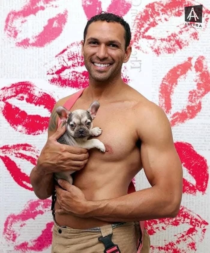 Hombre sonriente sostiene bulldog francés contra fondo de besos