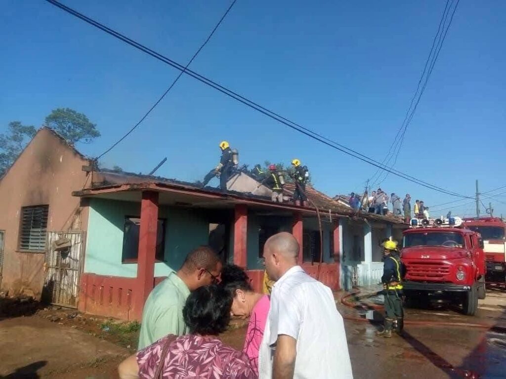 Bomberos trabajando en techo de casa incendiada