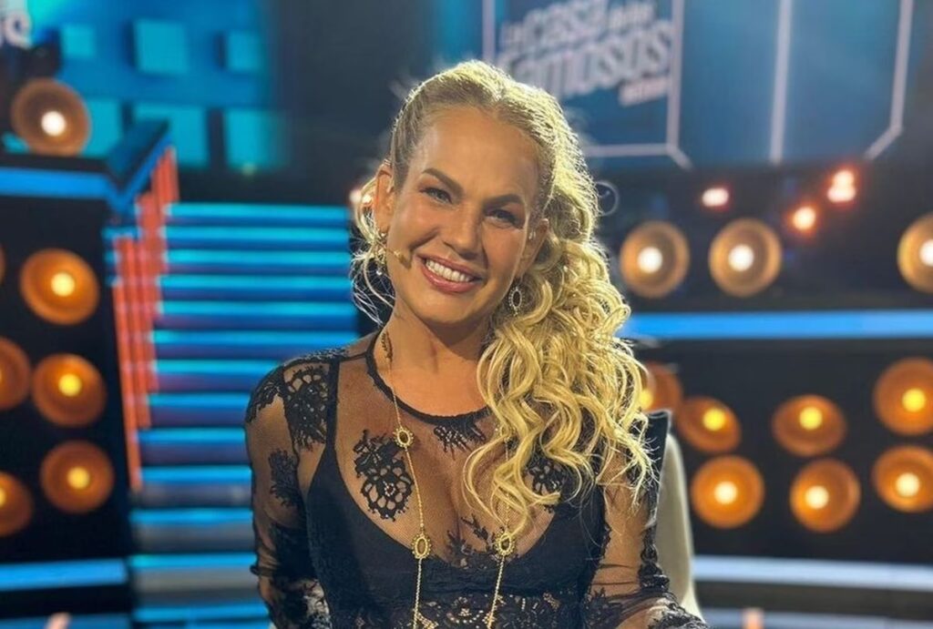 Mujer sonriente con vestido negro elegante en escenario