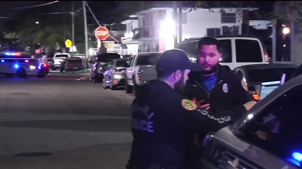 Policías hablando en calle nocturna con coches patrulla