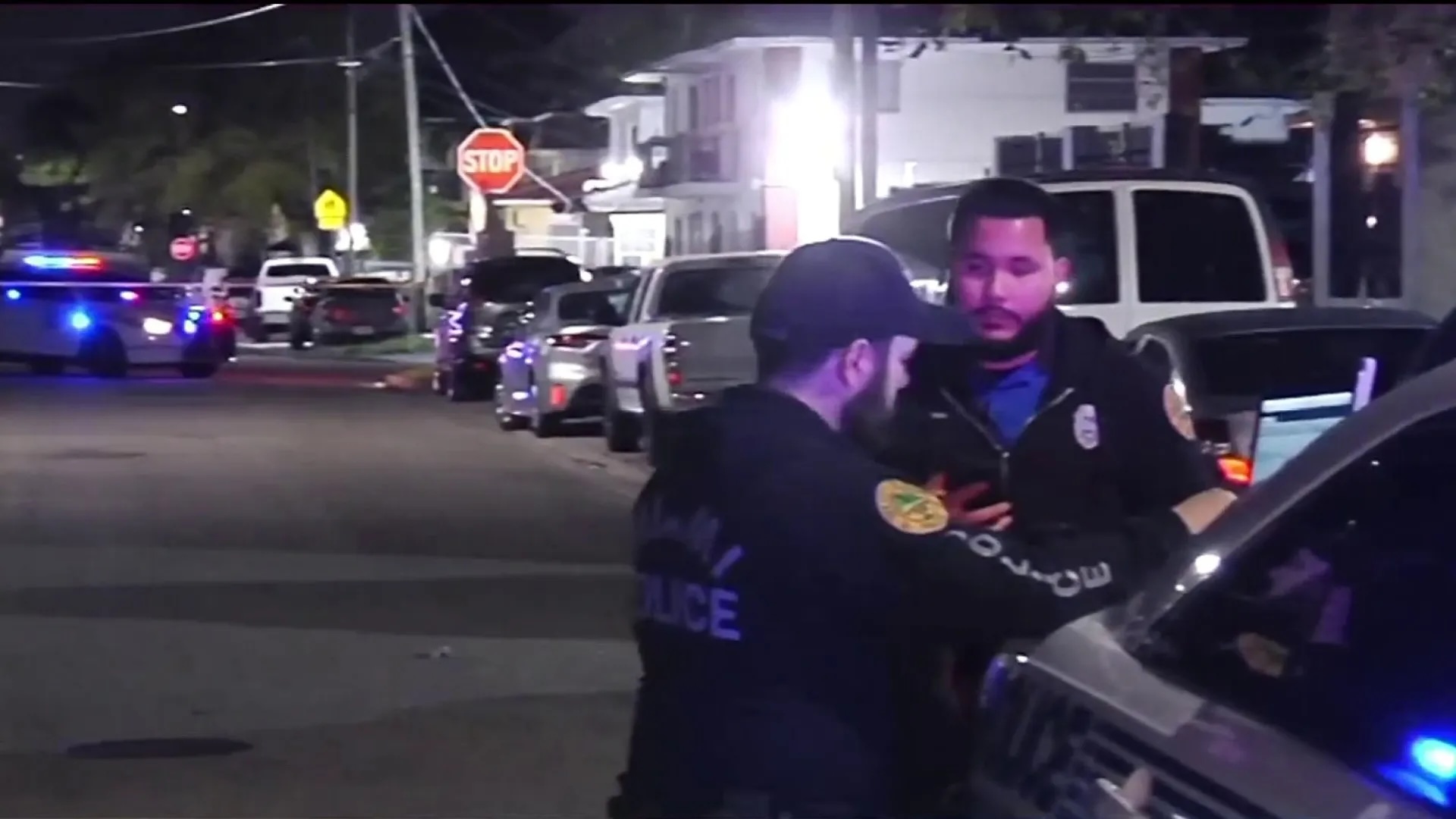 Policías hablando en calle nocturna con coches patrulla