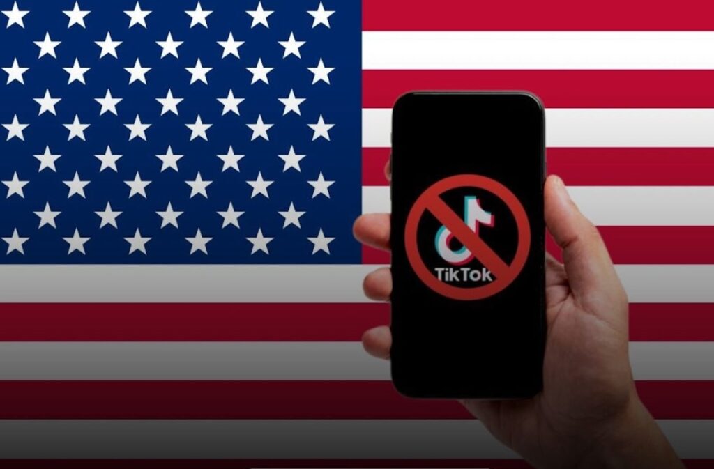Móvil mostrando logo de TikTok prohibido sobre bandera de EE.UU.