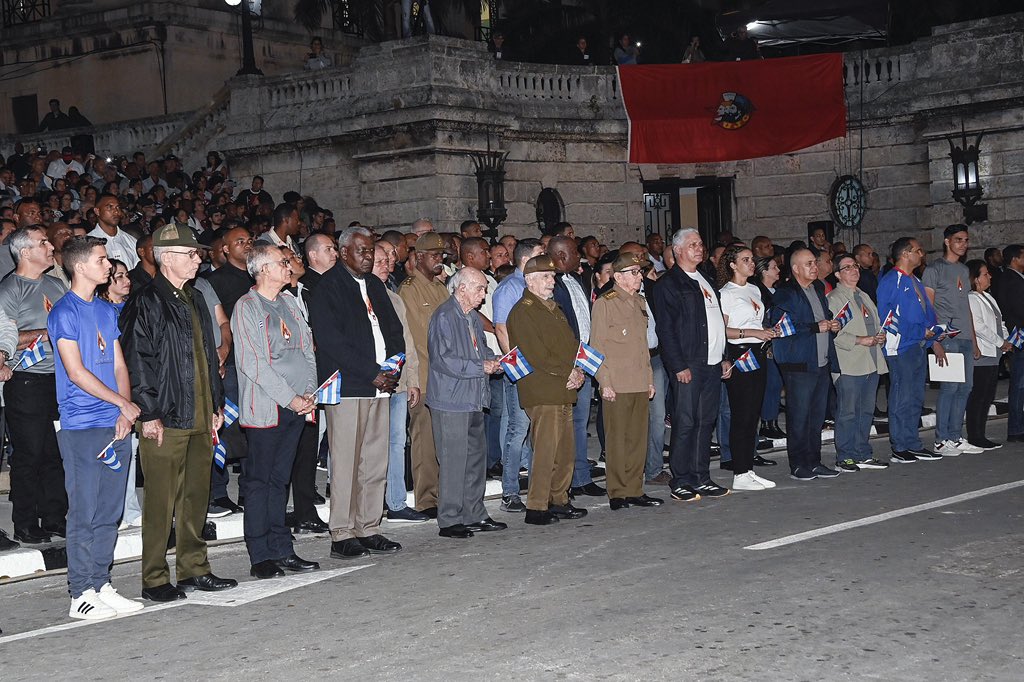 Grupo de personas con banderas en evento nocturno