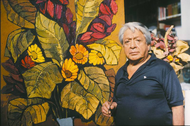 Hombre mayor junto a pintura grande de flores coloridas