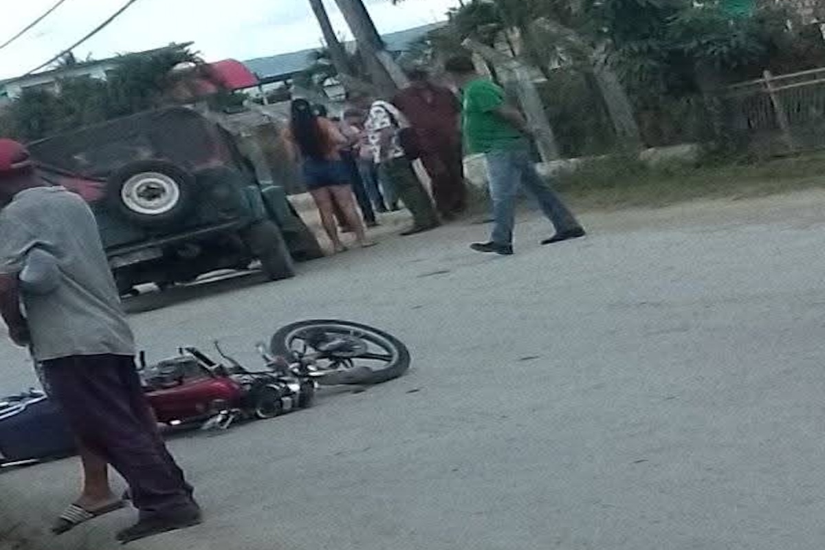 Personas alrededor de motocicleta caída en calle