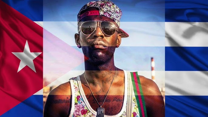 Hombre con gafas delante de bandera cubana.