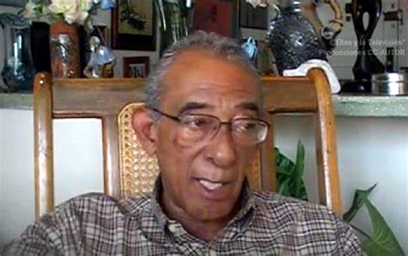 Hombre mayor hablando en interior, camisa de cuadros