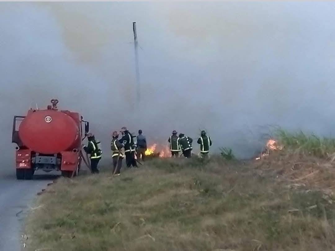 Bomberos apagando incendio en campo con camión cisterna