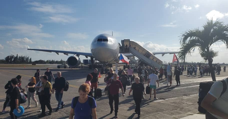 Pasajeros desembarcando de un avión en aeropuerto soleado