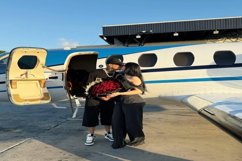 Pareja besándose junto a avión con ramo de rosas