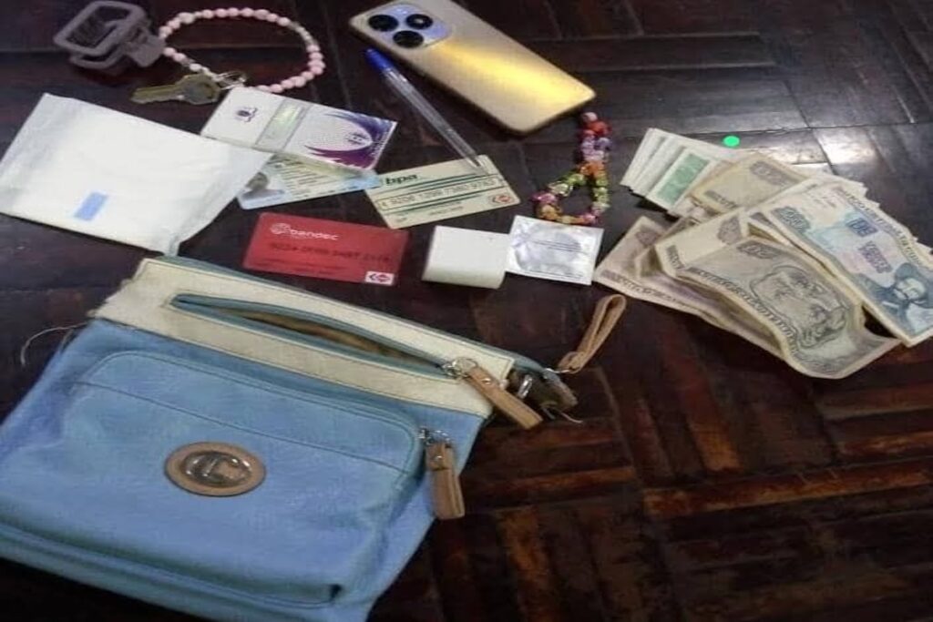 Objetos personales y dinero esparcidos sobre suelo de madera