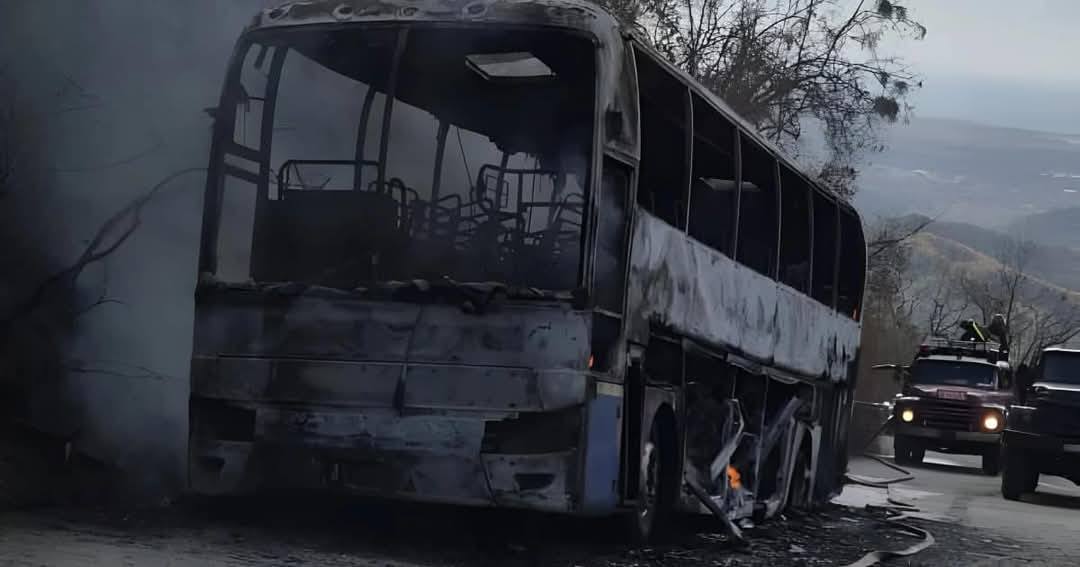Autobús quemado en carretera con humo