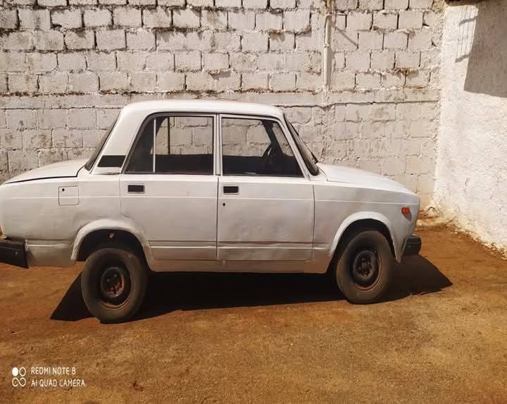 Coche antiguo blanco aparcado junto a pared