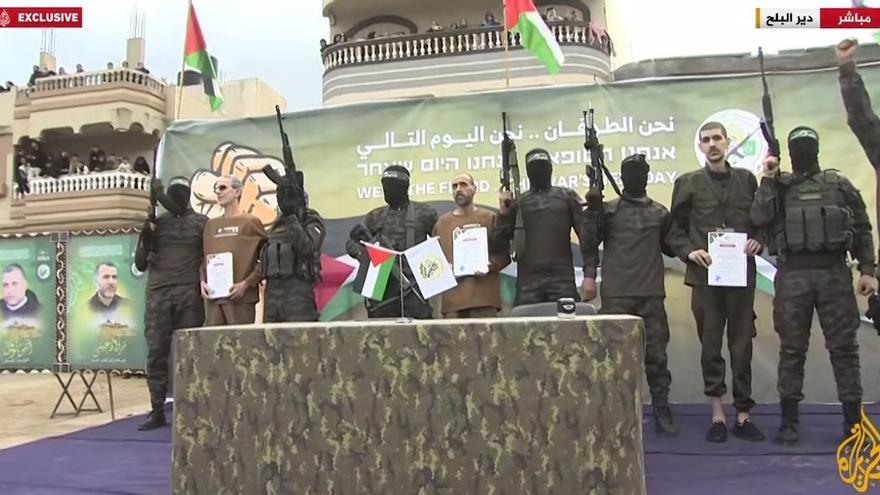 Grupo armado durante ceremonia con banderas y pancartas