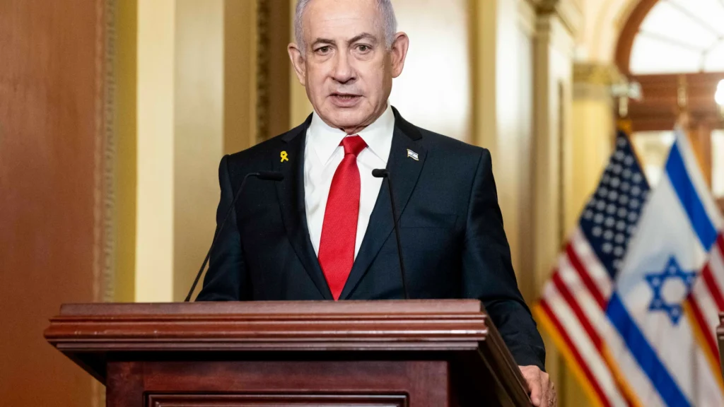 Hombre en podio con banderas de EE.UU. e Israel