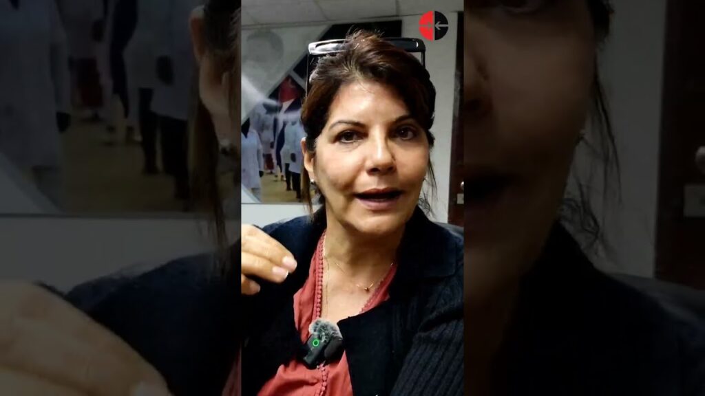 Mujer hablando a cámara en sala con mural.