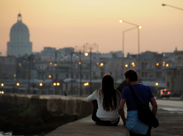 Pareja contemplando atardecer urbano desde muelle