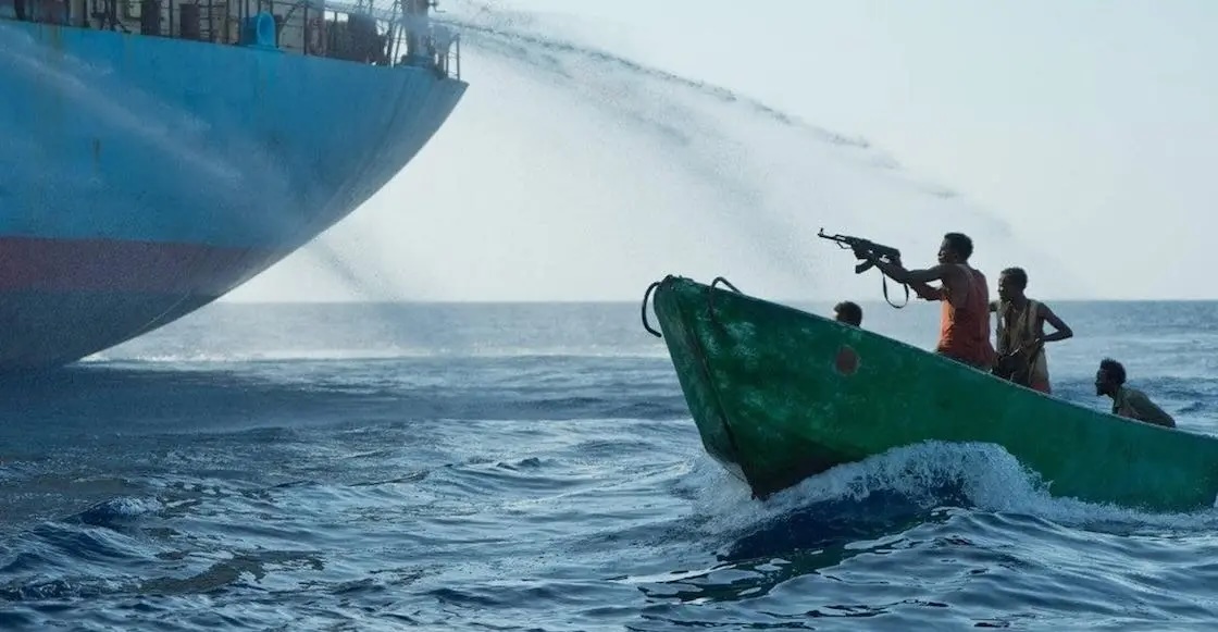 Barco grande rociando agua a bote pequeño con hombres