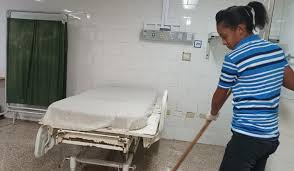 Persona limpiando un hospital con escoba