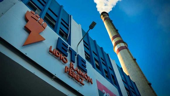 Fábrica industrial con chimenea humeante, cielo azul.