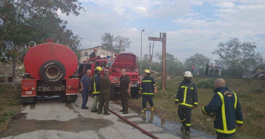 Bomberos trabajando junto a camiones en escena al aire libre.
