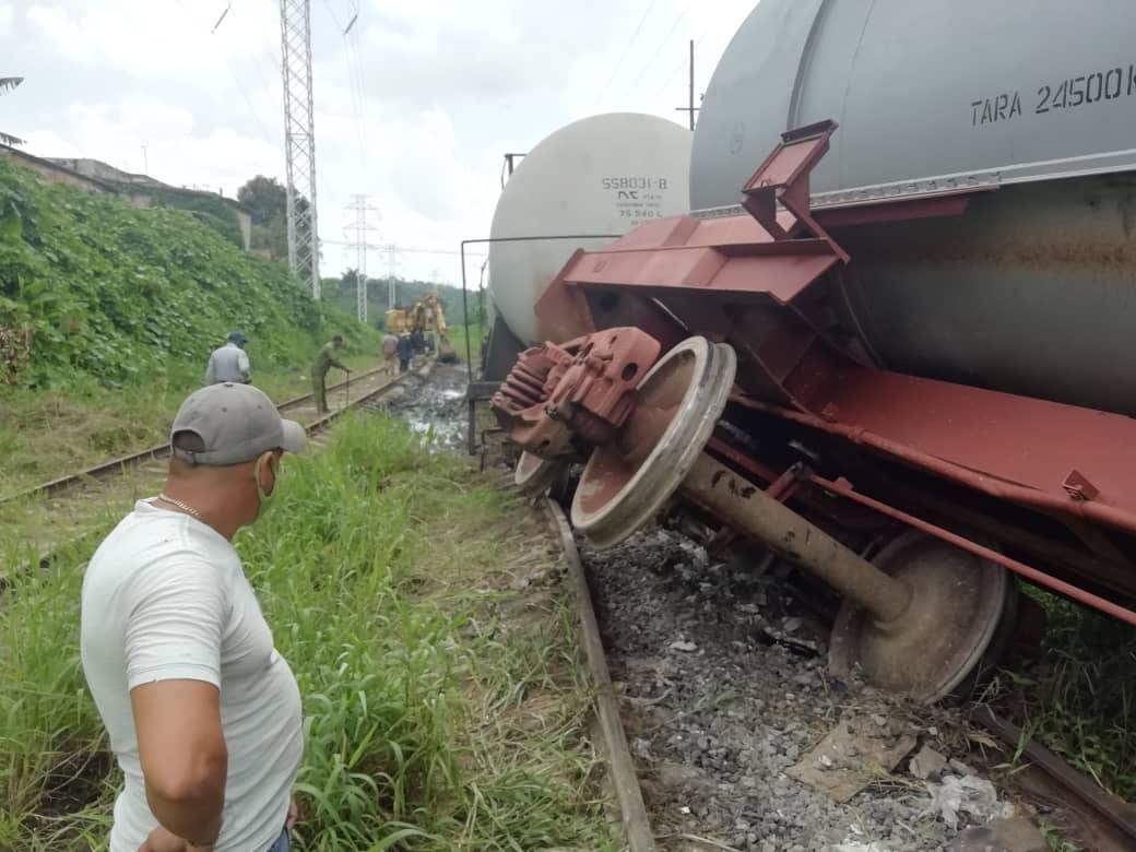 Accidente de tren fuera de las vías, personas observando.