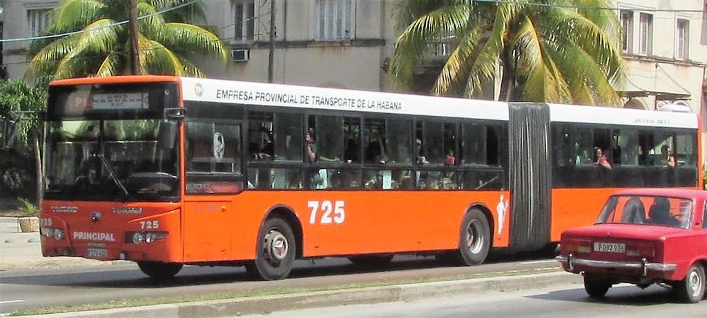 Autobús articulado naranja en calle de La Habana.