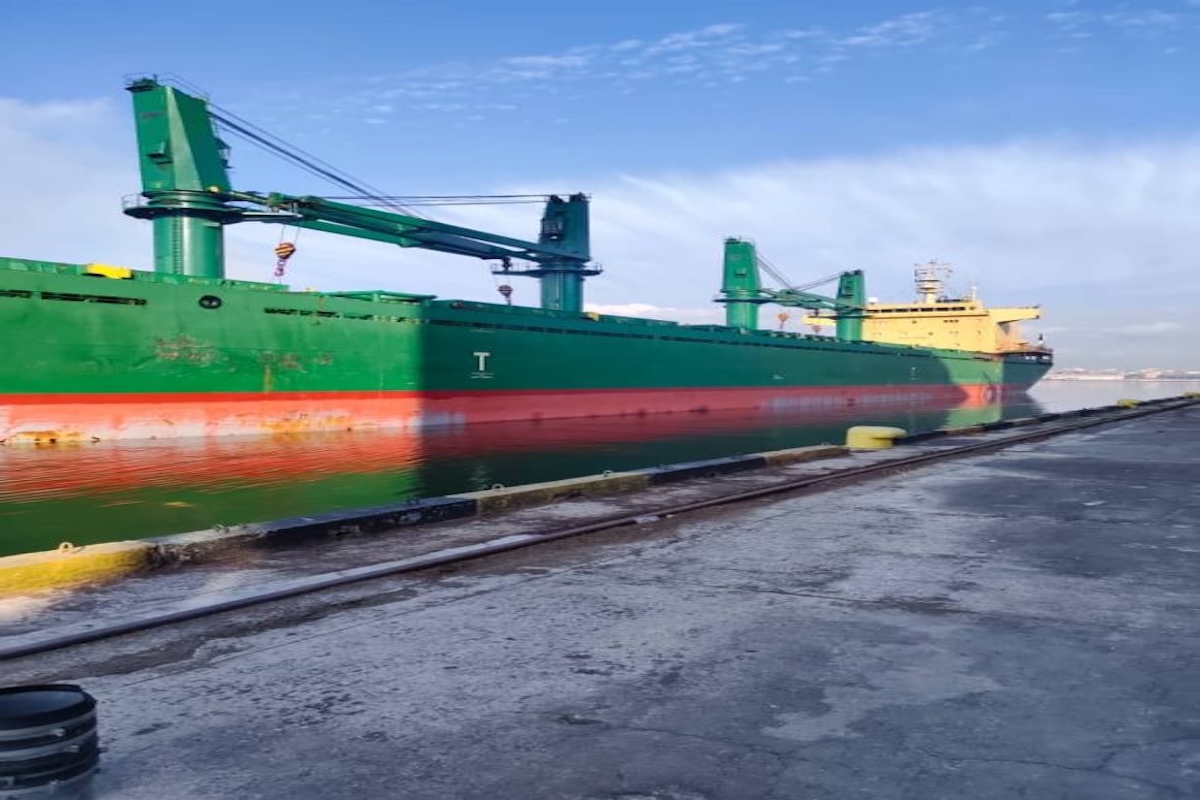 Barco carguero verde en muelle industrial