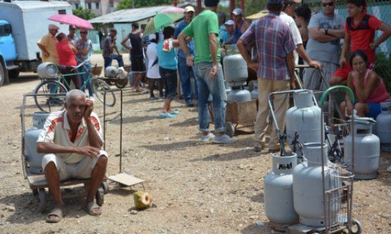 Gente esperando con bombonas de gas en calle