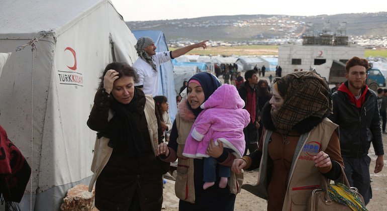 Refugiados en campamento temporal con tiendas de campaña.