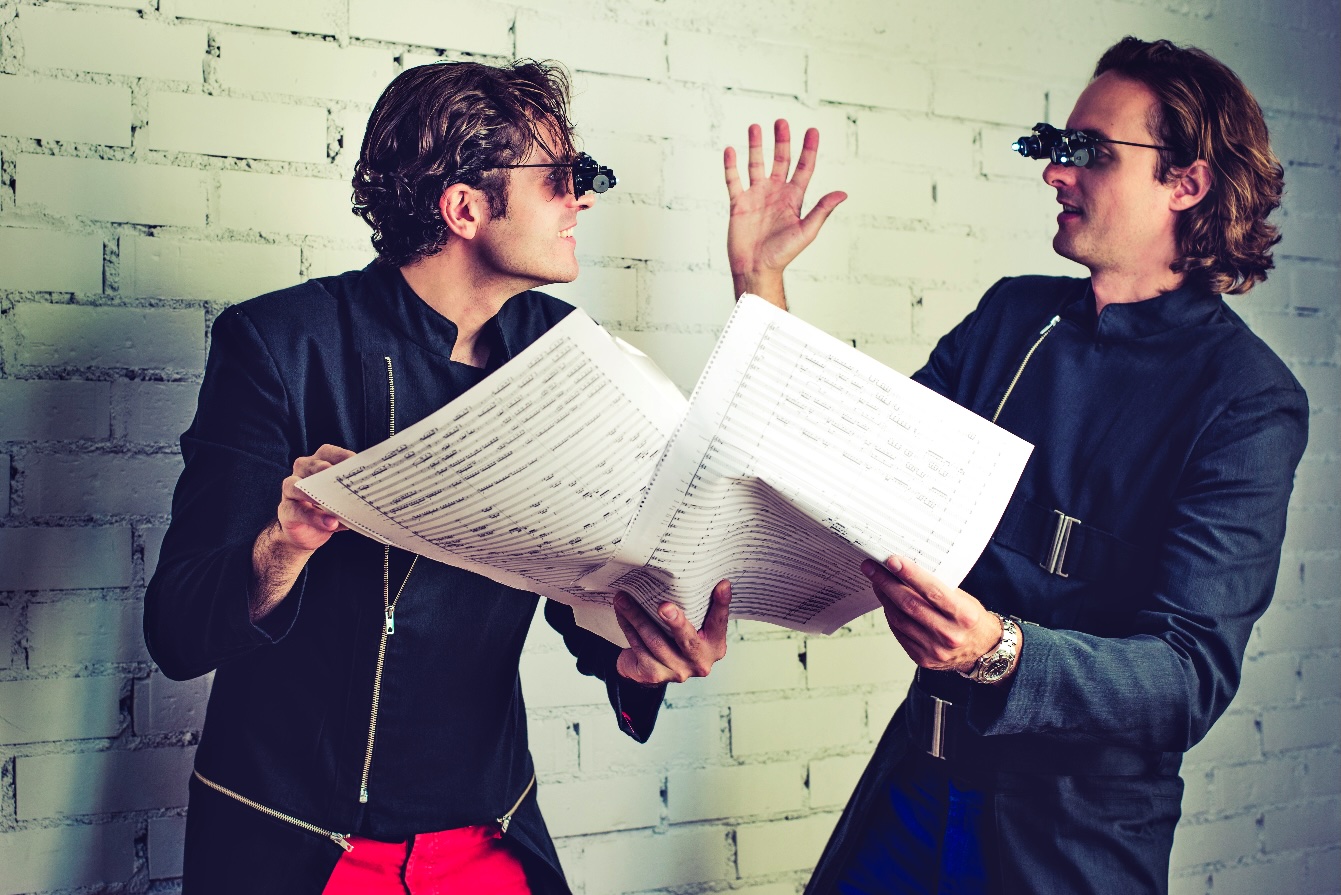 Dos personas discuten partituras musicales con gafas especiales.