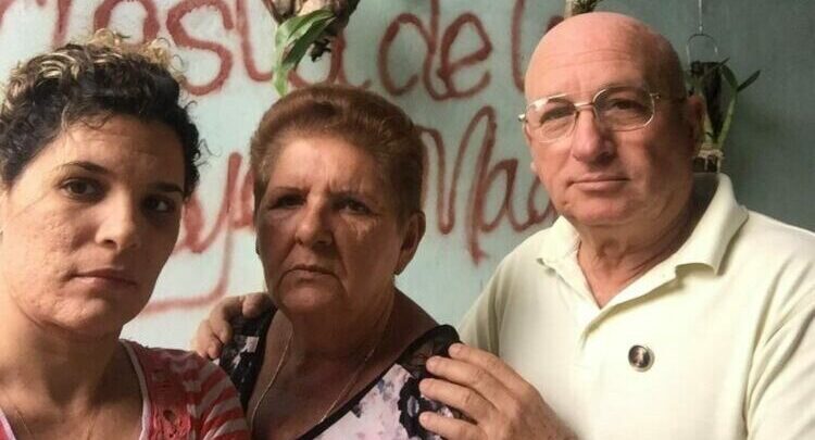 Tres personas mayores serias frente a graffitis rojos.