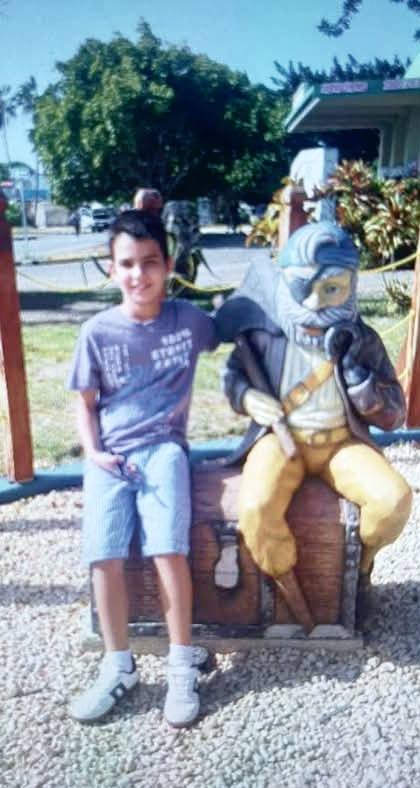 Niño junto a estatua de ratón pirata en parque