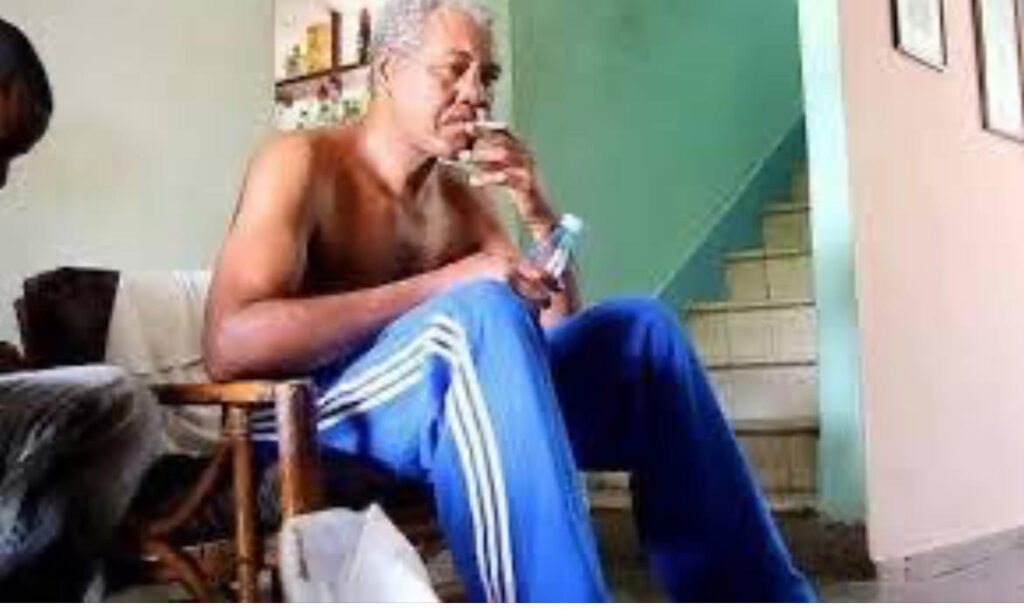 Hombre sentado en casa, sosteniendo botella.