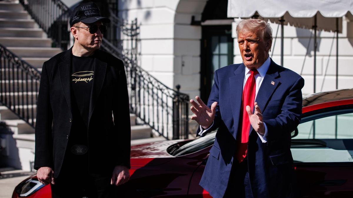 Dos personas hablando junto a un coche rojo.