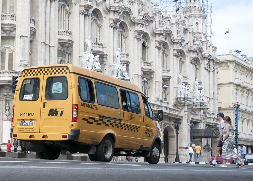 Taxi amarillo frente a edificio histórico en ciudad.