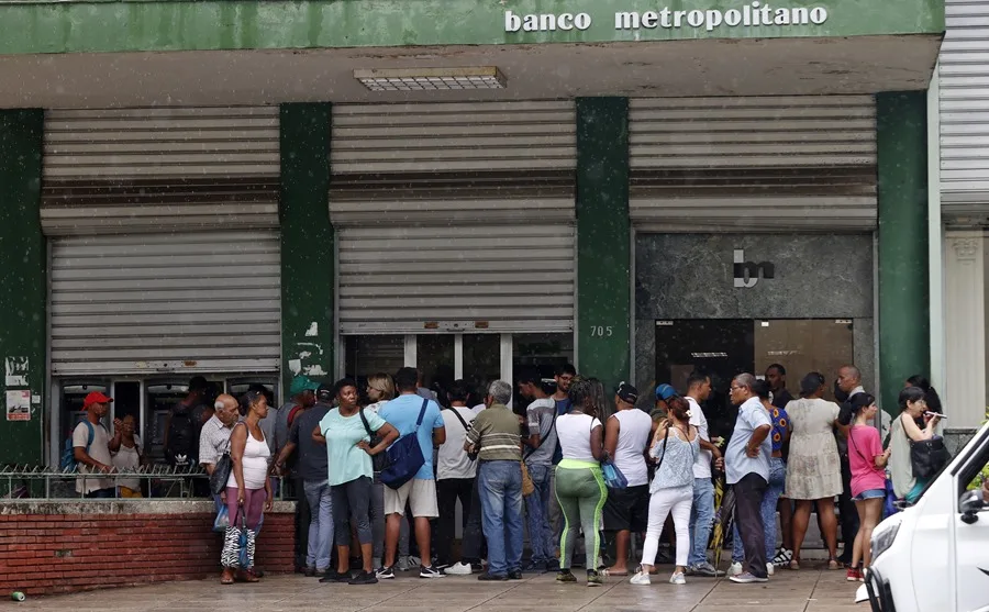 Personas hacen fila frente a banco cerrado